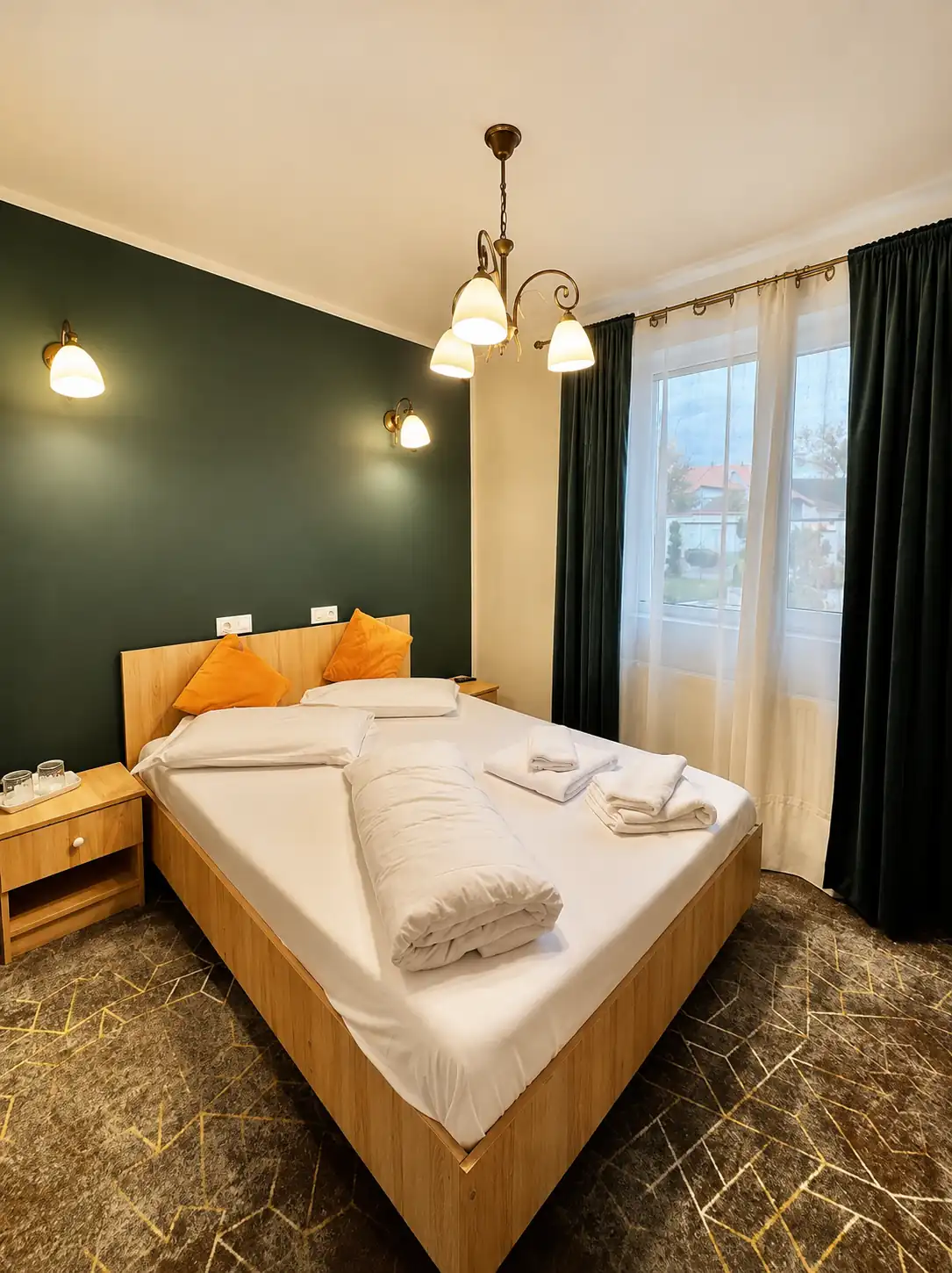 Double room with a wooden bed, green feature wall and daylight window