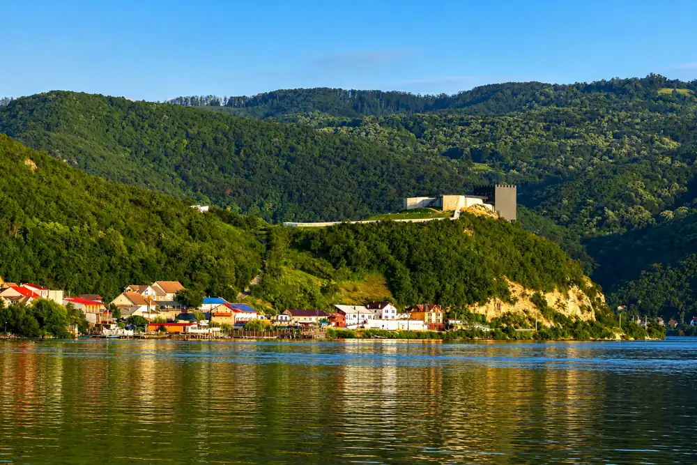Coronini village and the fortress hill seen from the calm Danube water