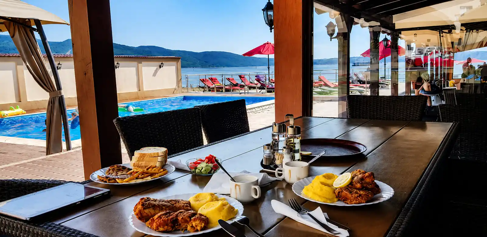 Breakfast served on the covered terrace beside the pool at Pensiunea Elis