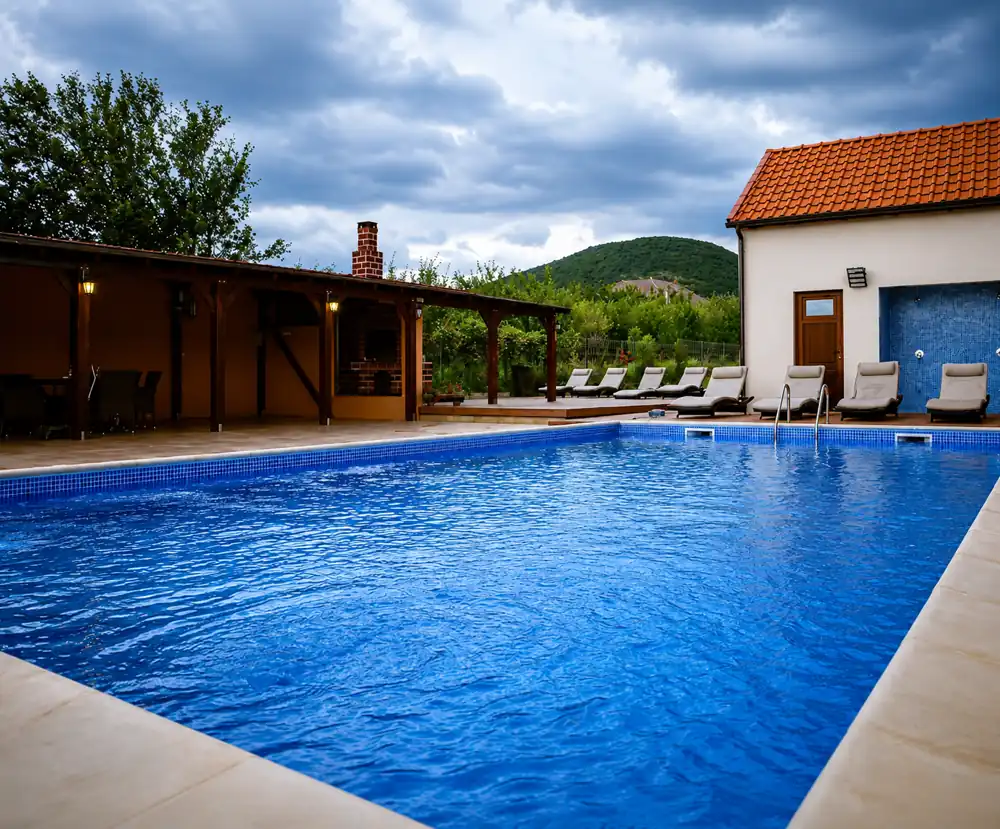 Outdoor swimming pool with loungers, pergola and the hills behind Pensiunea Elis