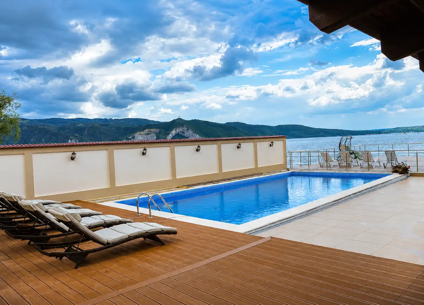 Outdoor pool and sun loungers above the Danube at Pensiunea Elis in Coronini