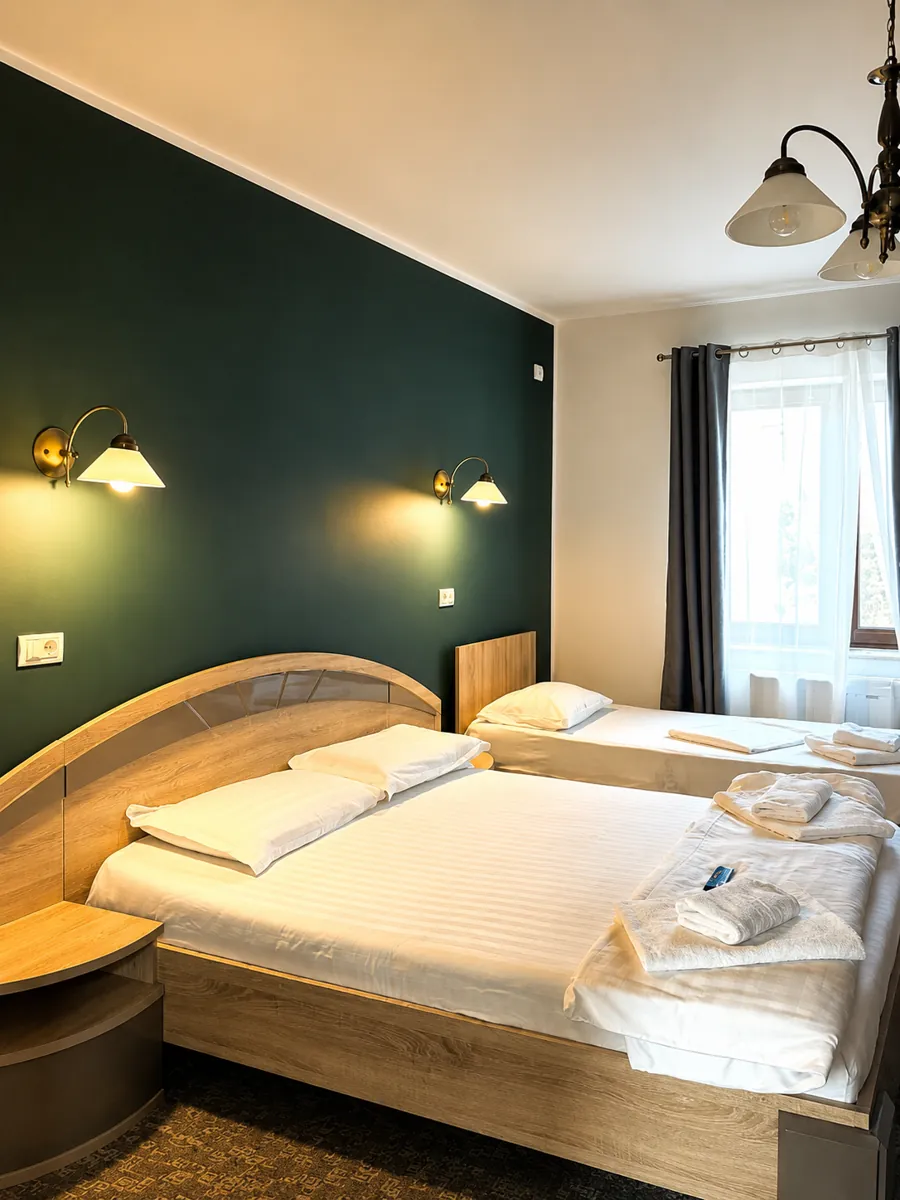 Family room with a double bed, single bed and dark green feature wall at Pensiunea Elis